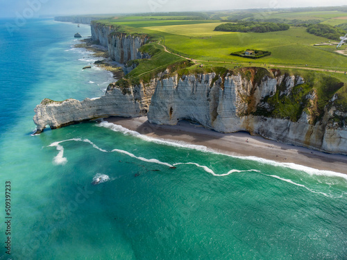 Fotografiet Aerian view on chalk cliffs near Porte d'Aval arch in Etretat on green meadows and blue water of Atlantic ocean, Normandy, France