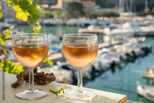 Cold rose wine in glasses served on outdoor terrace in sunlights with view on old fisherman's harbour with colourful boats in Cassis, Provence, France photo