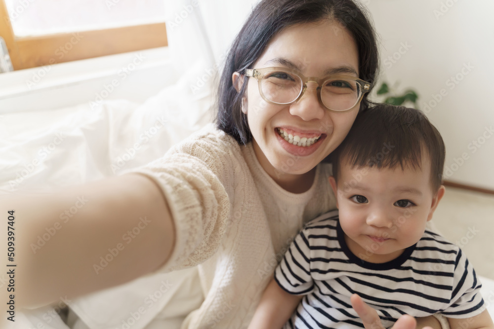 Chinese Young mother and her little cute son using smartphone taking selfie photos, Single Mom, Happy Asian family, Smiling Faces. Chinese Young mother and her little cute son using smartphone taking selfie photos, Single Mom, Happy Asian family, Smiling Faces.