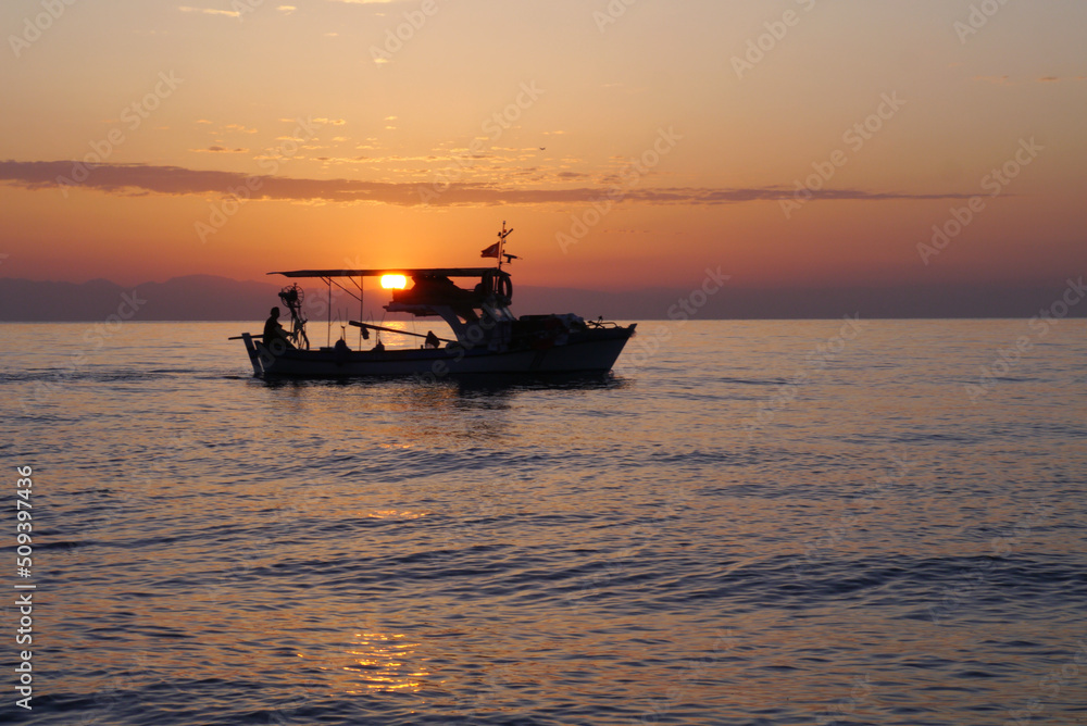 Silhouette of a fisherman's boat in the sea during sunrise