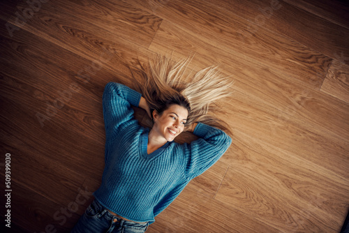 Fotografi Top view of happy woman lying on the floor at her new home.