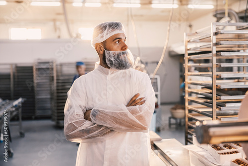 A food factory worker posing next to a table with fresh cookies.