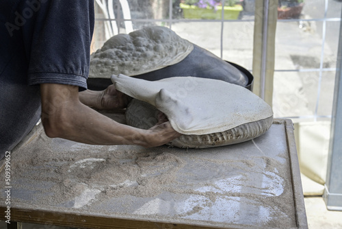 Hands putting dough to make a lafah, super thin arabic bread. photo