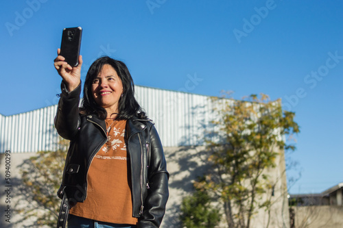 Fotografie adult latin woman entrepreneur on a farm outside production sheds taking a selfi