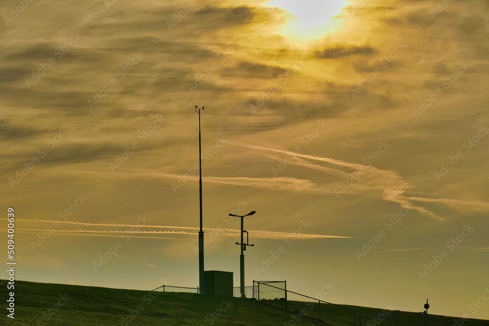 Obraz premium Silhouette of small weather station and metal fence, against an evening sky 