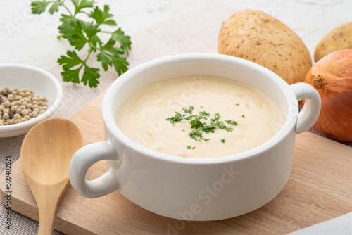 Bowl of creamy potato soup on wooden plate