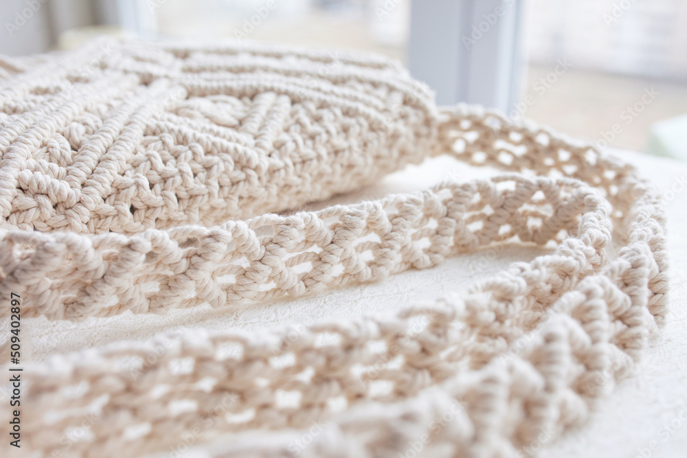 Fototapeta premium Handmade macrame cotton сross-body bag. Eco bag for women from cotton rope. Scandinavian style bag. Creme tones, sustainable fashion accessories. Details. Close up