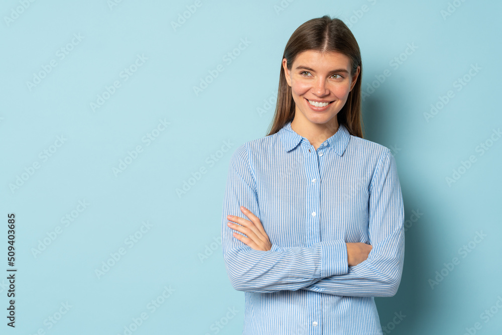 Pretty pensive smart confident girl standing with arms folded over blue background with copy space Pretty pensive smart confident girl standing with arms folded over blue background with copy space