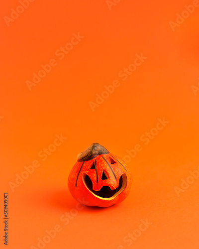 Decoration orange small smile Halloween pumpkin on orange blurred background and copy space. Holiday autumn concept backdrop.