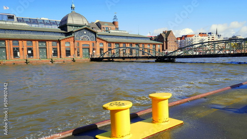 alte Fischauktionshalle in Hamburg - Altona an der Elbe mit gelben Pollern unter blauem Himmel