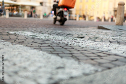 Stone pavement in perspective. Old street paved with stone blocks with white lines. Shallow depth of field. Vintage grunge texture. City ​​and people on background.
