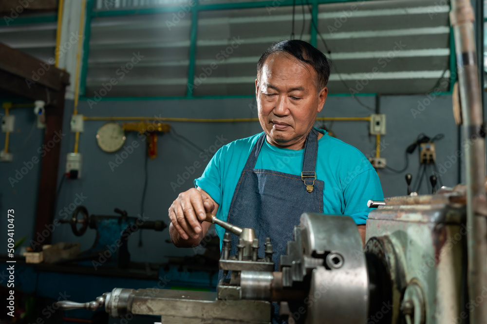 Portrait of a senior Asian man who is a steelworker. using a small steel turning tool to prepare for a lathe job in my family's small lathe. Portrait of a senior Asian man who is a steelworker. using a small steel turning tool to prepare for a lathe job in my family's small lathe.