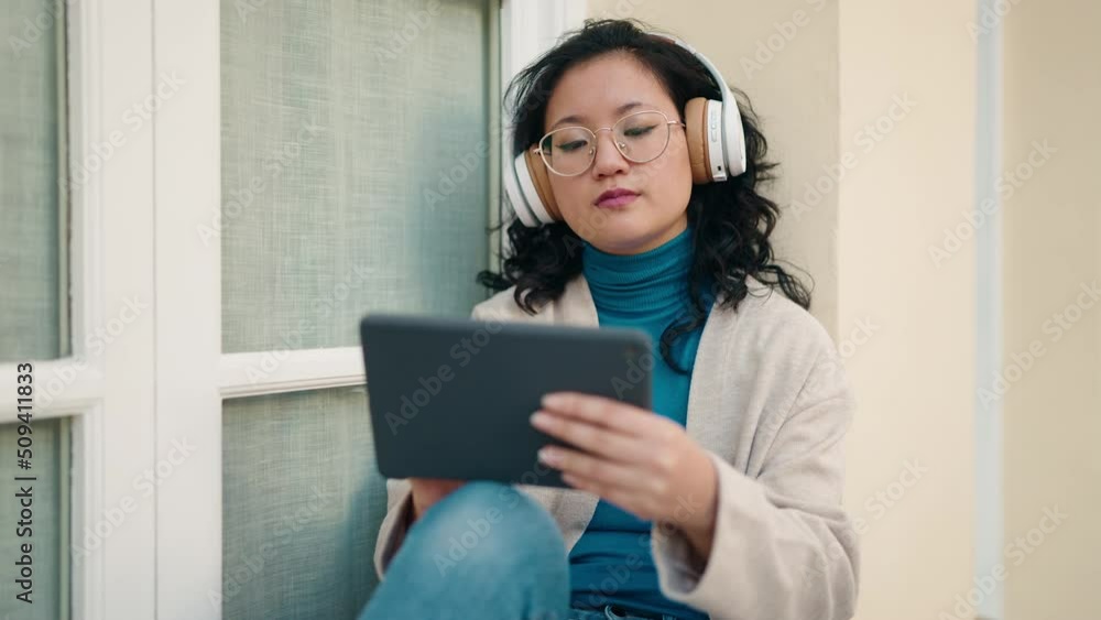 Young chinese woman using touchpad and headphones at street Young chinese woman using touchpad and headphones at street