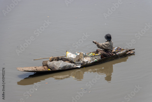 Photography A poor human floats on an old boat full of recycled materials