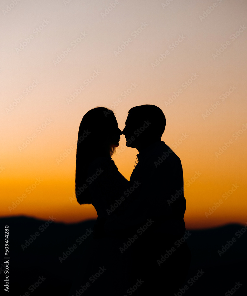 Silhouettes of a loving couple at sunset in the mountains