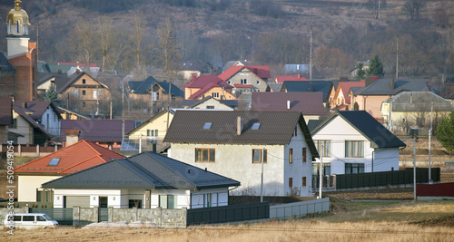 Residential houses with roof tops covered with metallic and ceramic shingles in rural suburban area
