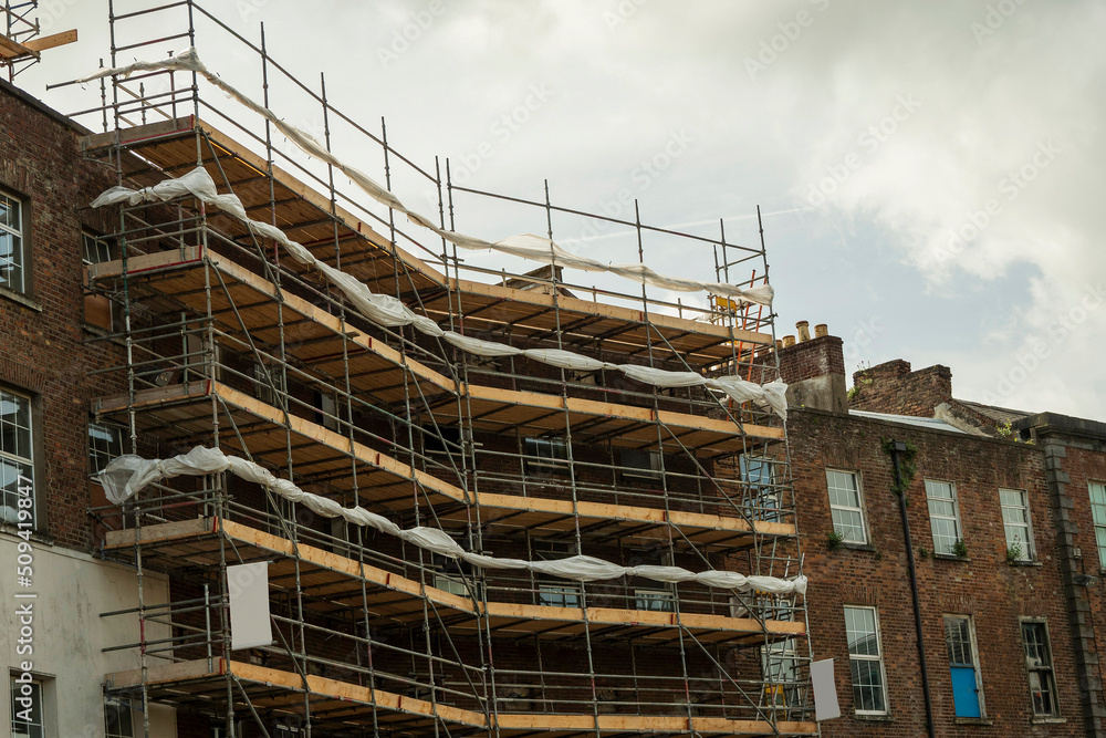 Modern home of office building construction with scaffolding. Cloudy sky background. New house development. Construction industry.