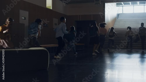 Group pupils running out classroom heading staircase. Teenagers leaving classes. photo