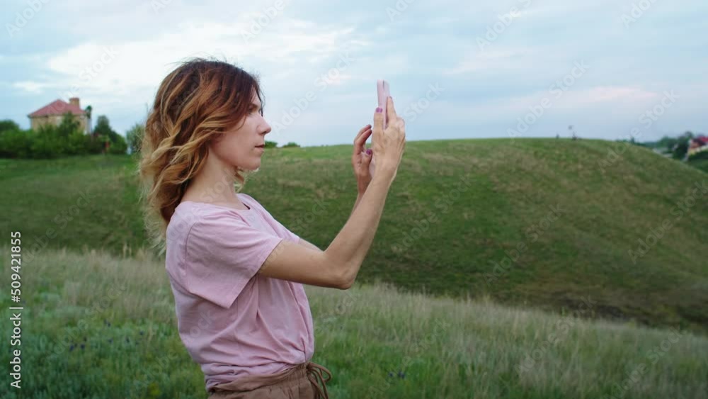 a young woman is happy to communicate in video communication through a phone on the mountain hills during sunset, for relaxation after a hike. rest of one person in nature, in the mountains. a young woman is happy to communicate in video communication through a phone on the mountain hills during sunset, for relaxation after a hike. rest of one person in nature, in the mountains.
