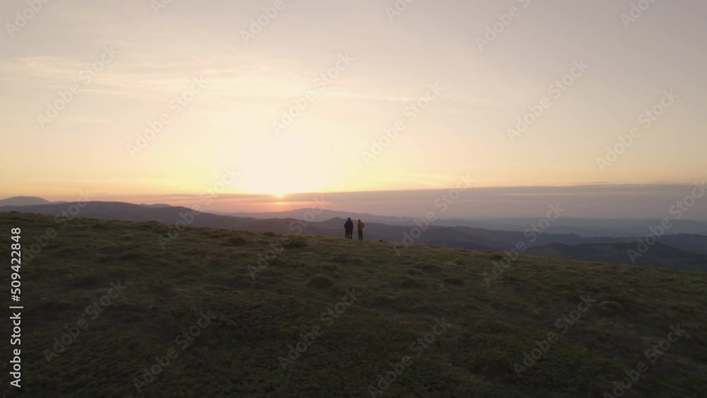 Aerial view of group of hikers sitting on the mountain top and watching the sunset Aerial view of group of hikers sitting on the mountain top and watching the sunset