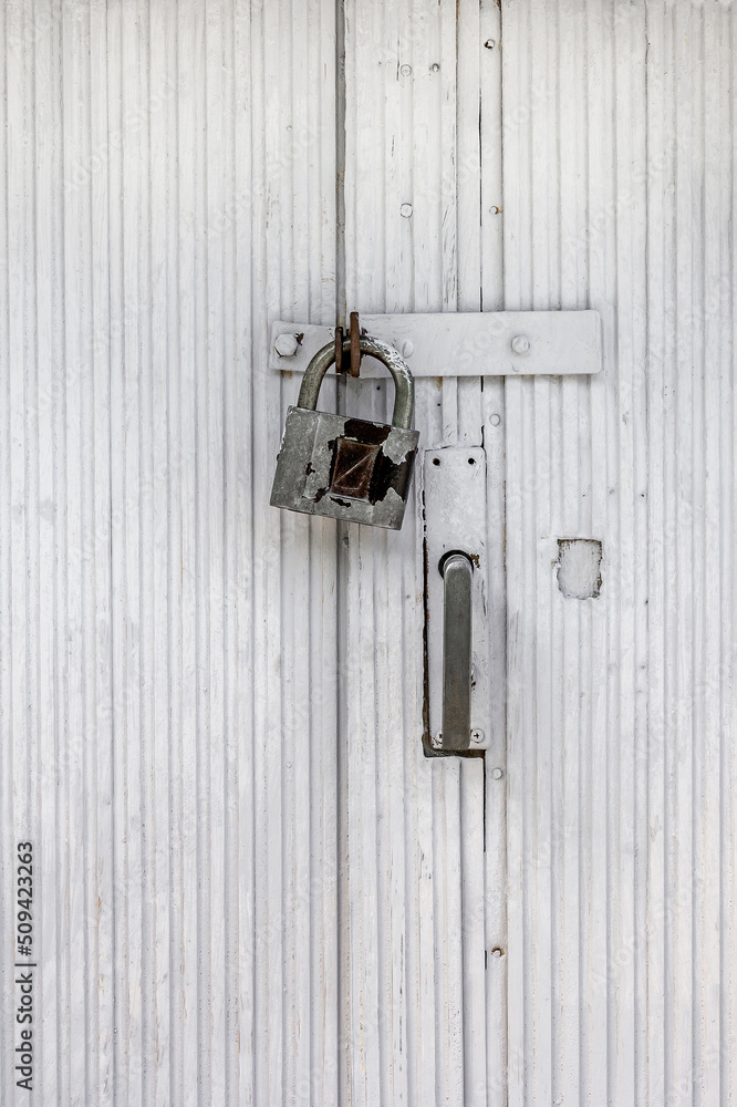 A rusty padlock hangs on an old painted wooden door A rusty padlock hangs on an old painted wooden door