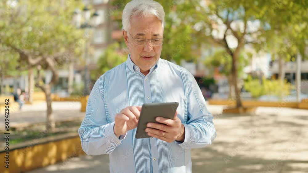 Senior man smiling confident using touchpad at park Senior man smiling confident using touchpad at park