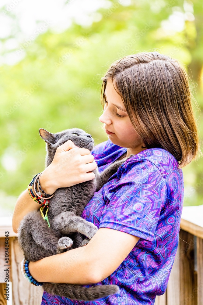 Young attractive girl holding a russian blue cat with sunny background