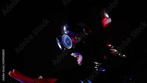 portrait of a crazy fetishist woman dancing in the dark in a latex mask