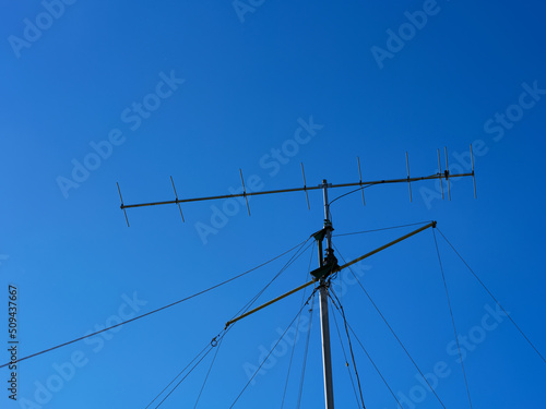 VHF radio antenna with stay ropes against blue sky