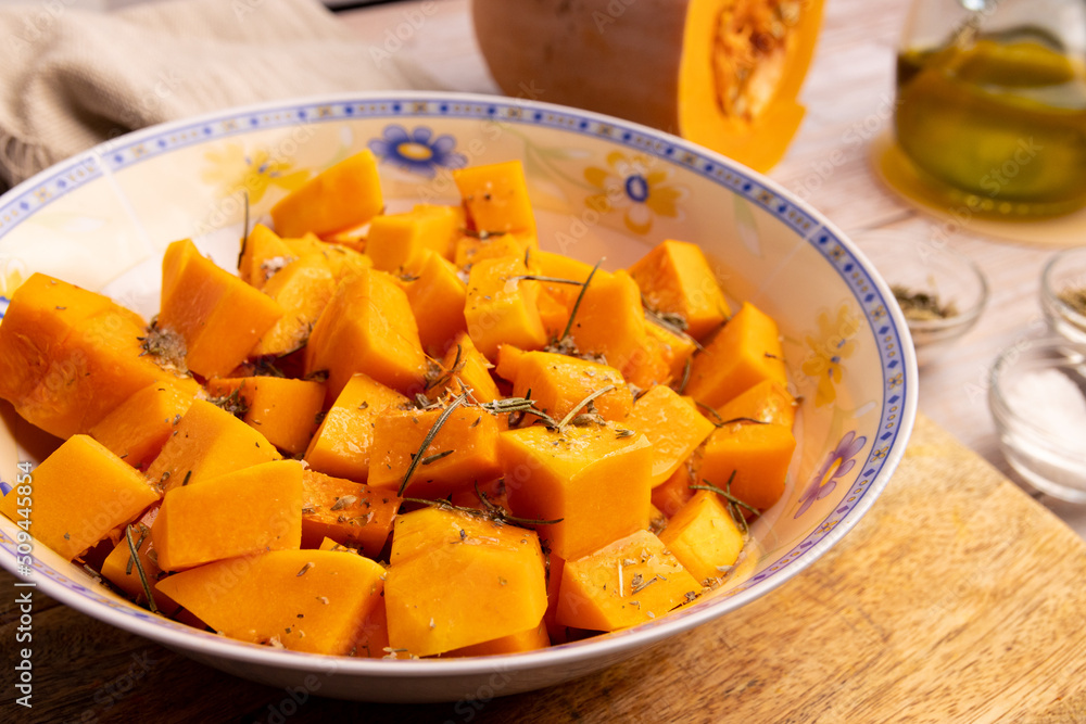 Diced pumpkin pieces in a bowl, with spices and olive oil Diced pumpkin pieces in a bowl, with spices and olive oil