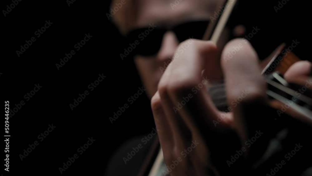 Slow motion close-up of young single caucasian blonde male violinist in black suit and glasses playing violin with bow, moving, sliding and tapping fingers on strings, dark stage blurry background. Slow motion close-up of young single caucasian blonde male violinist in black suit and glasses playing violin with bow, moving, sliding and tapping fingers on strings, dark stage blurry background.