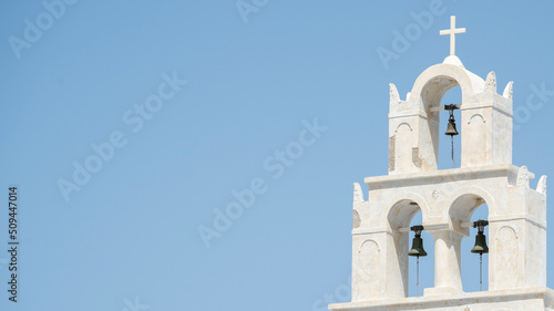 White colored greek orthodox church with bells and roof cross during a sunny summer day © MARIO MONTERO ARROYO