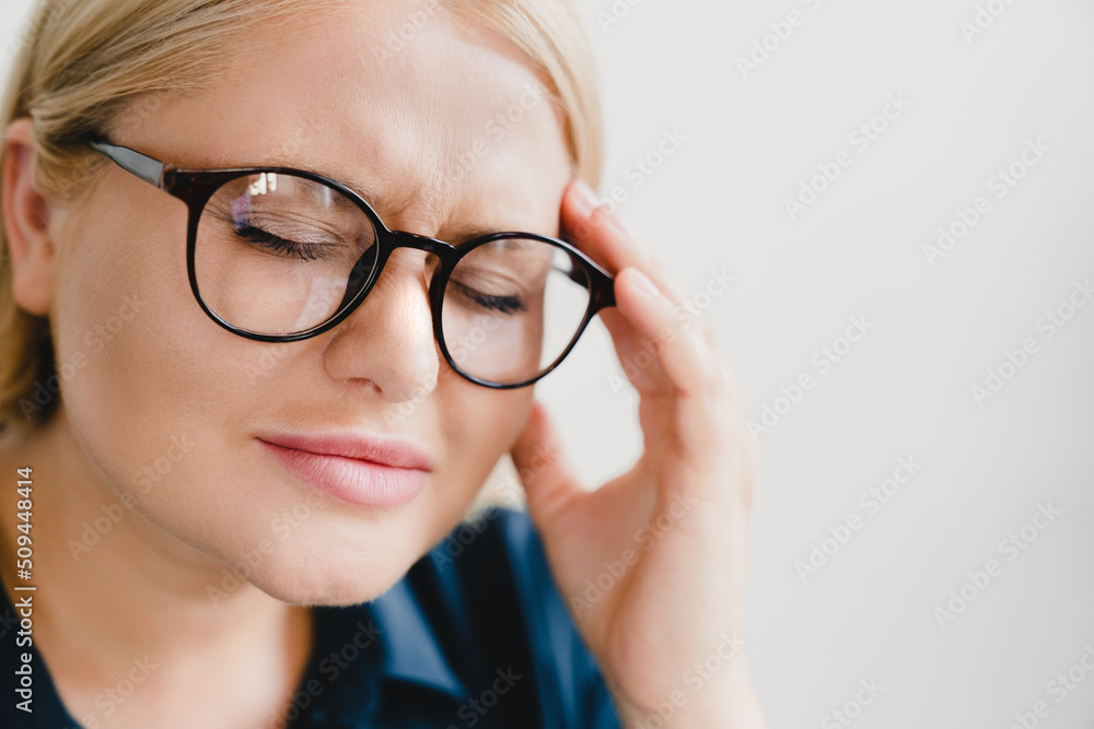 Closeup cropped tired sad depressed after workload caucasian young businesswoman female employee teacher student suffering from migraine, headache, rubbing temples with eyes closed Closeup cropped tired sad depressed after workload caucasian young businesswoman female employee teacher student suffering from migraine, headache, rubbing temples with eyes closed