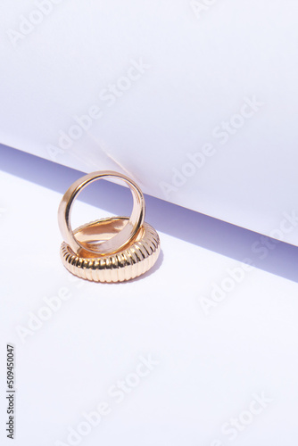 Two gold wedding rings on a white background with contrasting shadows. Close up