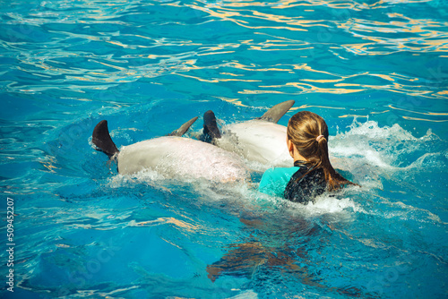 Happy girl rides with dolphins. Healthy lifestyle