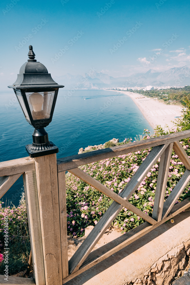 Famous Konyaalti beach, scenic panoramic view from a cliif top. Decorative lantern and wooden fence. Travel destinations of Turkey and Antalya and mediterranean riviera