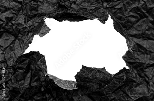 Texture of crumpled black crumpled paper with a hole in the center. Paper with free space for writing