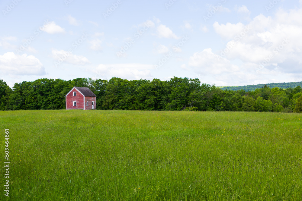 Pretty landscape along route 247 with small derelict red cabin in the middle of a green field in spring, Stanstead, Quebec, Canada Pretty landscape along route 247 with small derelict red cabin in the middle of a green field in spring, Stanstead, Quebec, Canada
