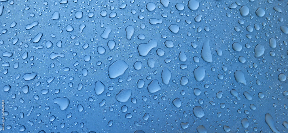 A drop of water on the hood of the car. Water beads after rain or car wash on blue paint surface.