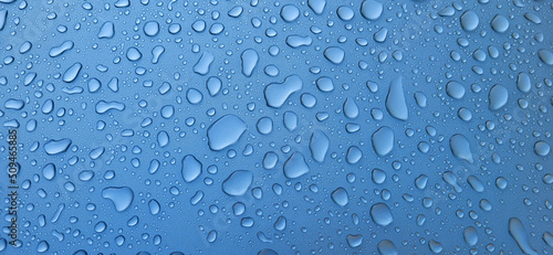 A drop of water on the hood of the car. Water beads after rain or car wash on blue paint surface.