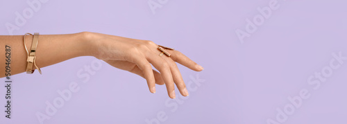 Hand of beautiful woman wearing stylish jewellery on lilac background with space for text