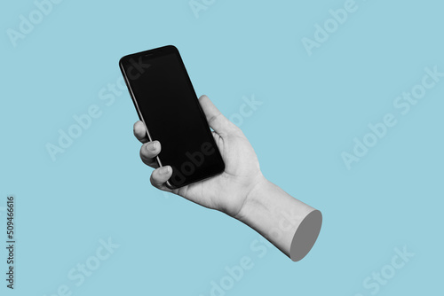 Mobile phone with black screen in female hand isolated on a blue color background. Blank with an empty copy space for the text. Trendy collage in magazine urban style. Contemporary art. Modern design photo