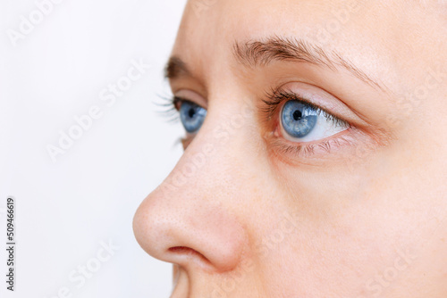 Fototapeta Naklejka Na Ścianę i Meble -  Cropped shot of a young woman's face with blue eye lenses isolated on a white background. The girl wearing contact lenses. Beauty, vision, ophthalmology