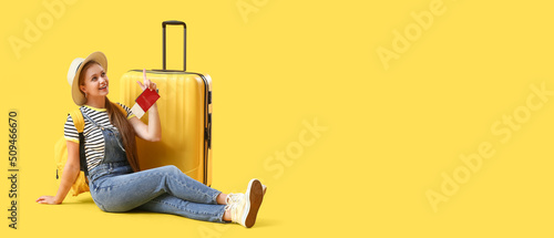Fotografia, Obraz Female traveler with suitcase on yellow background