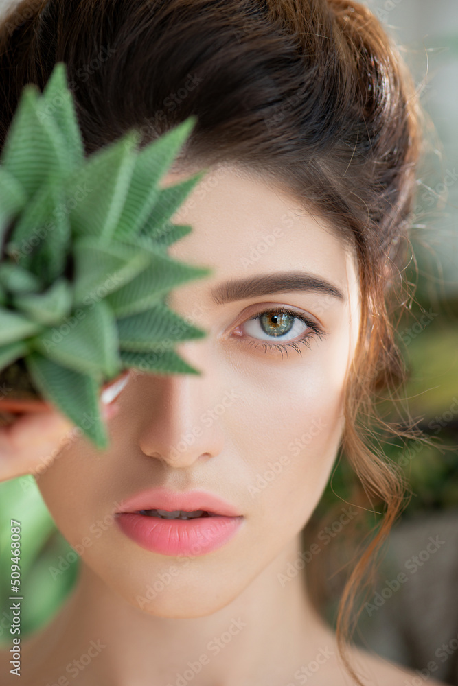 Beautiful young woman's face with perfect skin with tropical cactus. Beauty girl in SPA and wellness, body care and skincare concept. Close up, selective focus Beautiful young woman's face with perfect skin with tropical cactus. Beauty girl in SPA and wellness, body care and skincare concept. Close up, selective focus