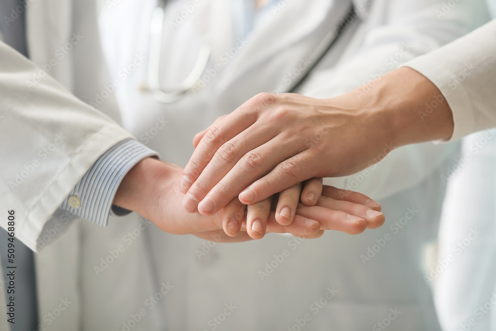 Group of doctors putting hands together in clinic, closeup Group of doctors putting hands together in clinic, closeup