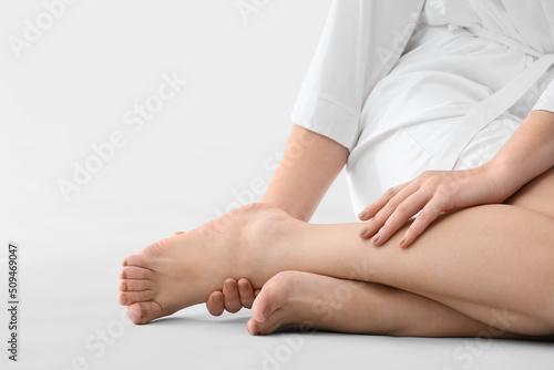 Young woman making foot massage on light background  closeup