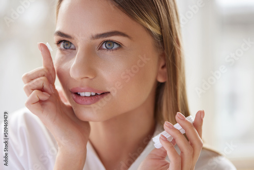 Eye care. Smiling Woman With Contact Eye Lens on Finger Closeup. Portrait of Beautiful Blonde Girl Putting Contacts Lenses in Eyes. Vision Health Concept