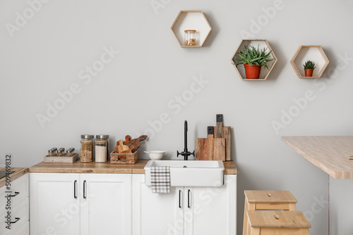 Counters with kitchen utensils, sink and food near light wall