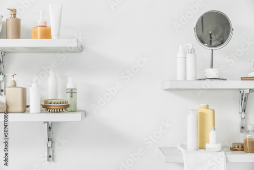 Shelves with bath accessories hanging on light wall